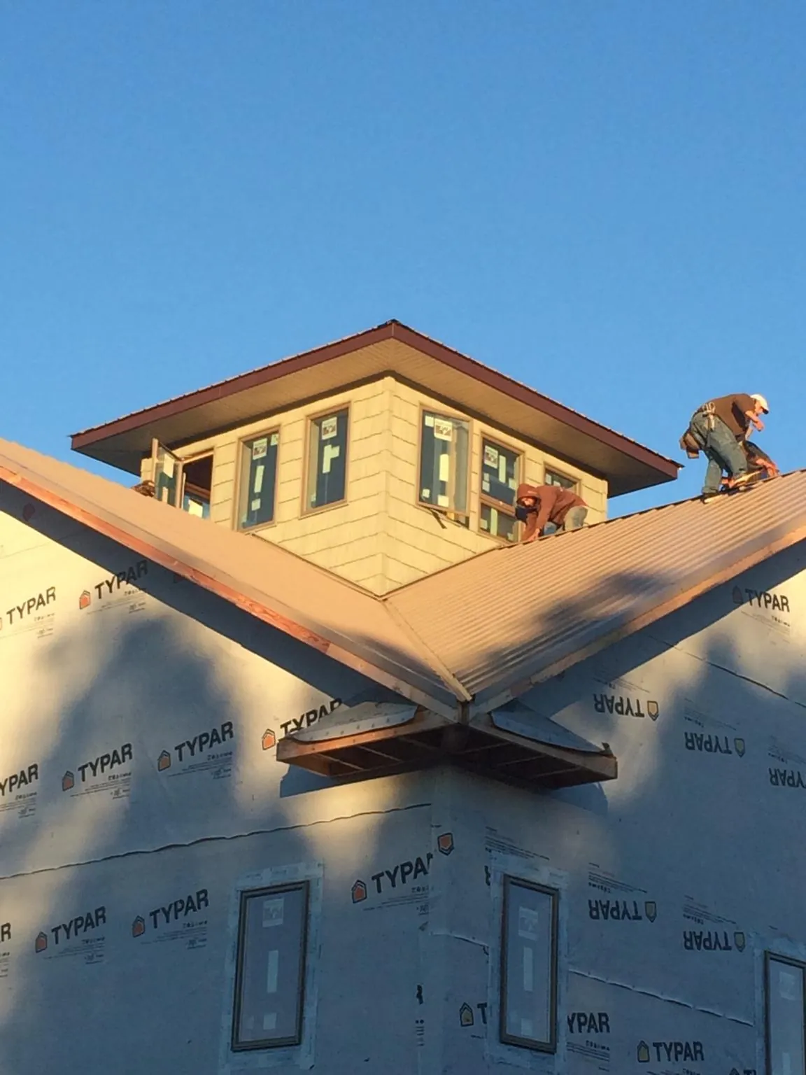 Roofers working around a rooftop cupola on a new metal roof at sunset — Roof Waterproofing in Ormond Beach by Roofing Brothers